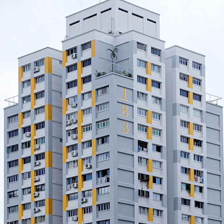 Hochhaus mit grauer Fassade und gelben Akzenten, zahlreiche Fenster sichtbar.