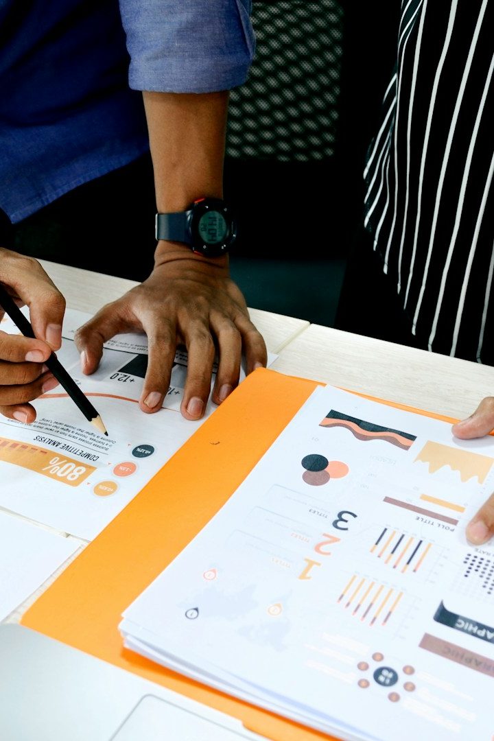 Zwei Personen arbeiten an Diagrammen und Notizen auf einem Tisch.